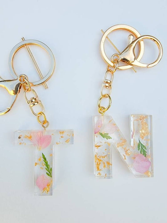 Pink flower petals and gold flakes in clear letter keychain. gold clasp keychain